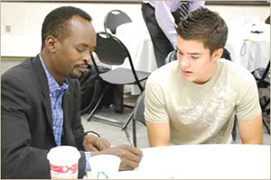An image with a mentor with his student reviewing paperwork